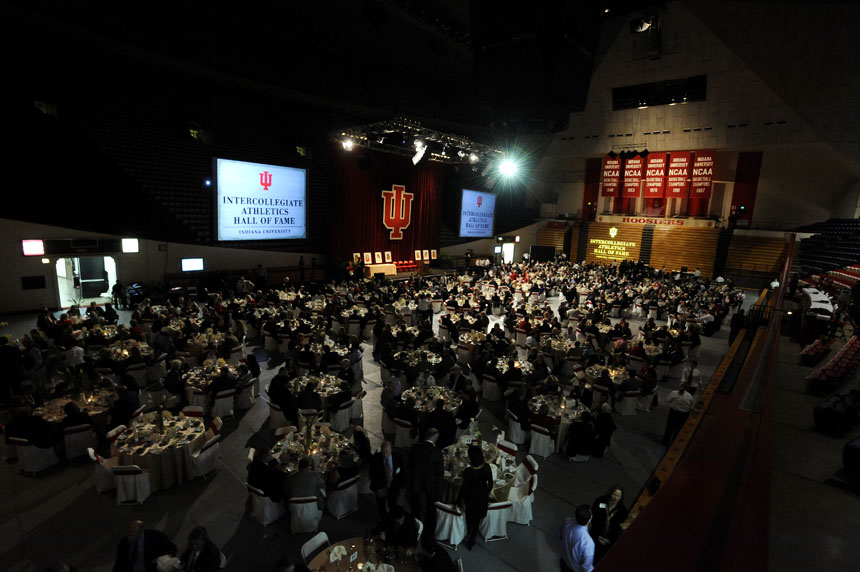 People eat before the start of the Indiana University Athletics Hall of Fame induction ceremony on Friday, Nov. 6, 2009, at Assembly Hall in Bloomington, Ind. Three of IU's five men's basketball national championship banners, seen at right, came under former coach Bob Knight, who is among those inducted. Knight declined an invitation to the induction ceremony.