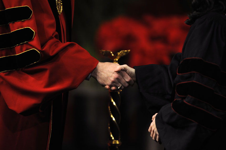 IU President Michael McRobbie, left, shakes hands with a doctoral candidate during IU's Winter Commencement Exercises on Saturday, Dec. 19, 2009, at Assembly Hall. At IU's May Commencement, administrators did not shake hands with students due to growing concerns at the time about H1N1.