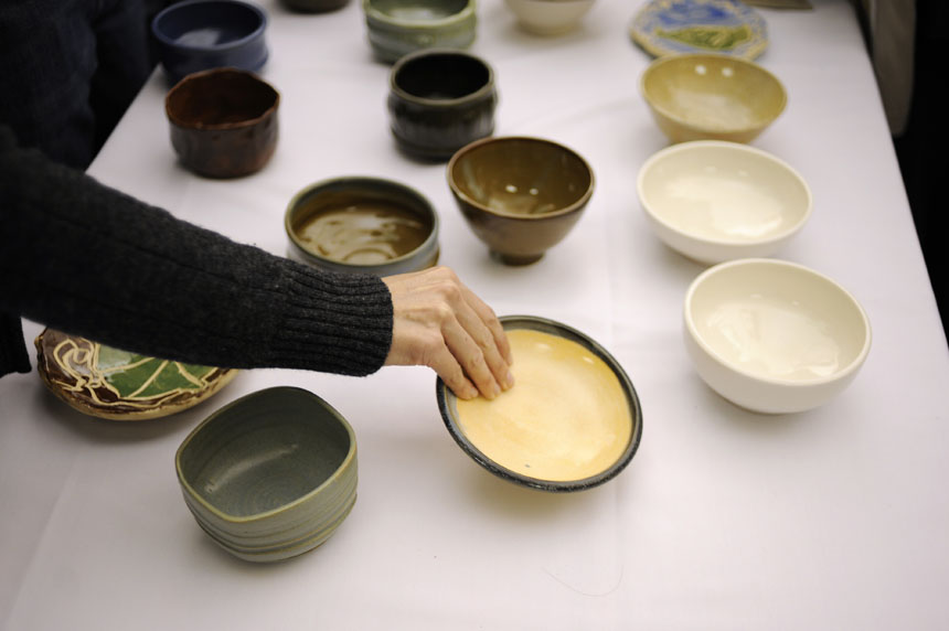 A woman reaches for a bowl during the 16th Annual Soup Bowl on Sunday, Feb. 21, 2010, at the Bloomington Convention Center. Patrons selected soup bowls made by local artists.