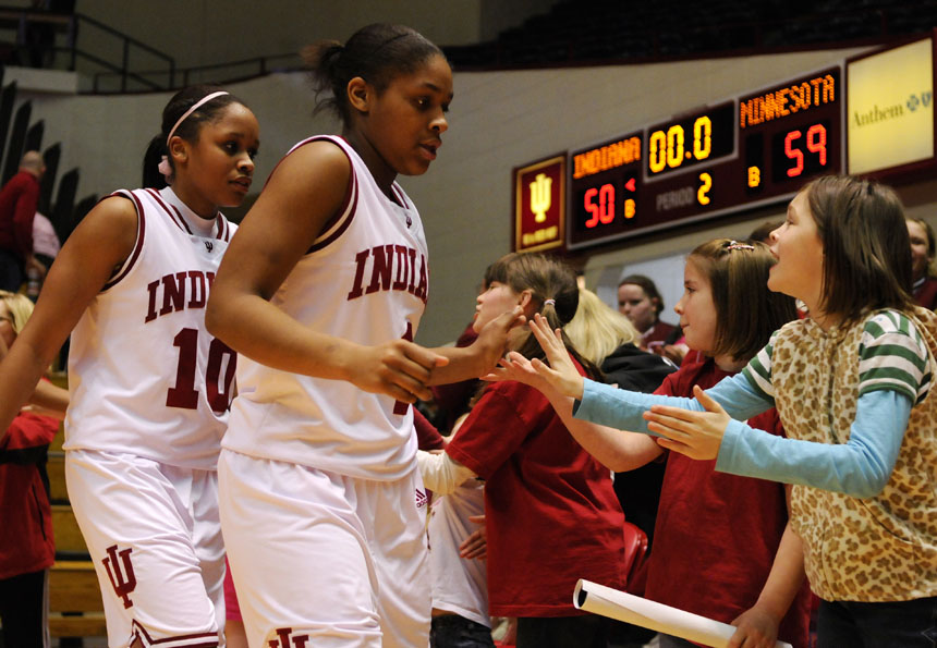 IU guards Ashlee Mells, right, and Andrea McGuirt slap hands with children sitting on the floor after a 59-50 loss to Minnesota on Sunday, Feb. 21, 2010, at Assembly Hall. Win or lose, the team makes its way past the floor seats greeting fans as they head back to the locker room.