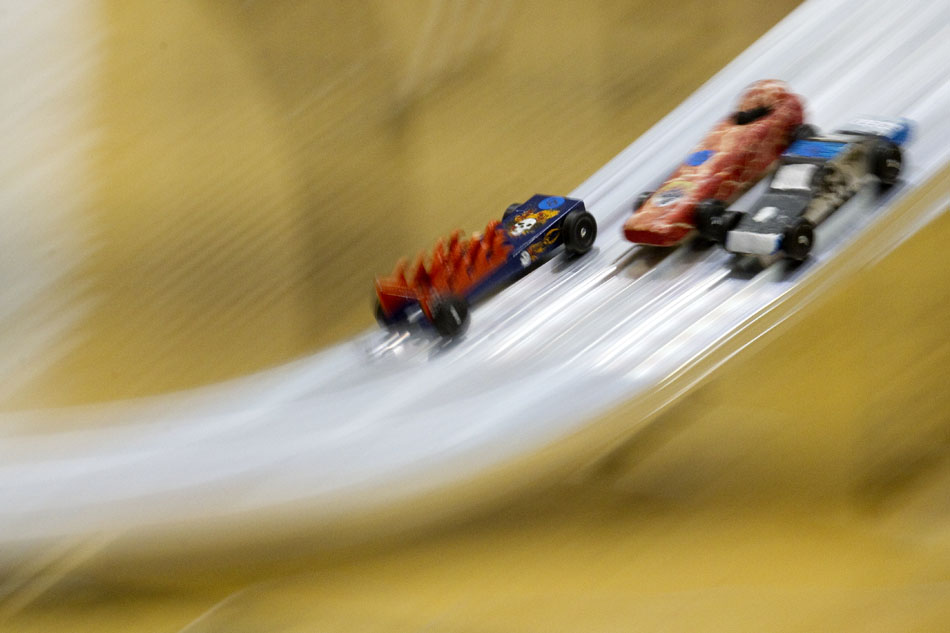 Pinewood derby cars race down the track during a heat on Saturday, April 23, 2011, at Storey Gym.