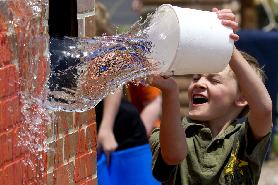 Jackson Hamm, age 8, tosses a bucket of water through a window at a bucket brigade activity during a kids cowboy festival on Saturday, June 11, 2011, at Frontier Park. The bucket activity proved to be one of the most popular activities for several kids at the event.