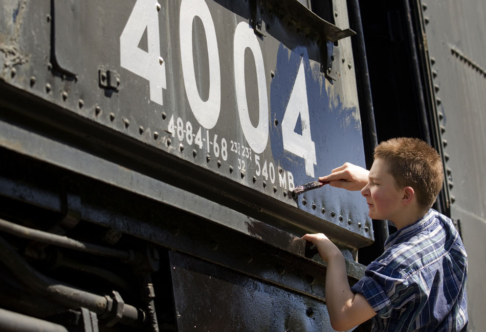 Alex Frye, 13, carefully applies a coat of black paint around identifying numbers on the Big Boy train on Monday, Sept. 5, 2011, in Holliday Park. Members of the Sherman Hill Model Railroad Club spent the day applying fresh paint to the train, one of eight existing 4000-class Union Pacific trains still in existance today.